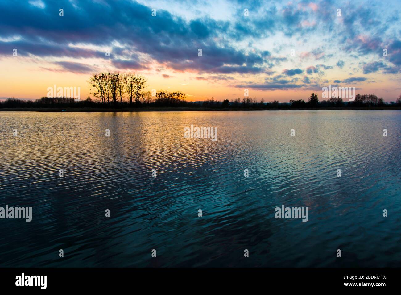 Bunte Wolken nach Sonnenuntergang über dem See, Bäume am Horizont, Stankow, Lubelskie, Polen Stockfoto