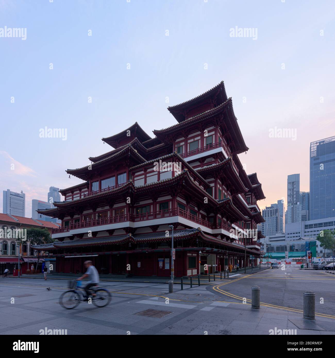 Singapur - 31. Okt 2019: Ein Mann fährt bei Sonnenaufgang vor dem chinesischen Tempel Buddha Tooth Relic in der Innenstadt von Singapur Fahrrad Stockfoto