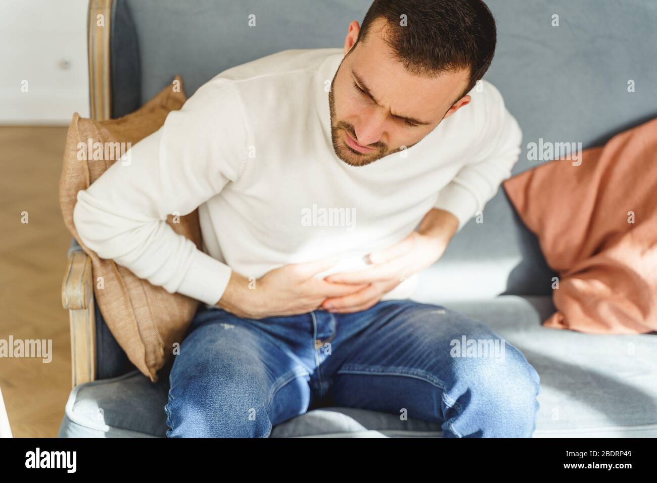 Junger Mann writthing in einem Magenschmerzen Stockfoto