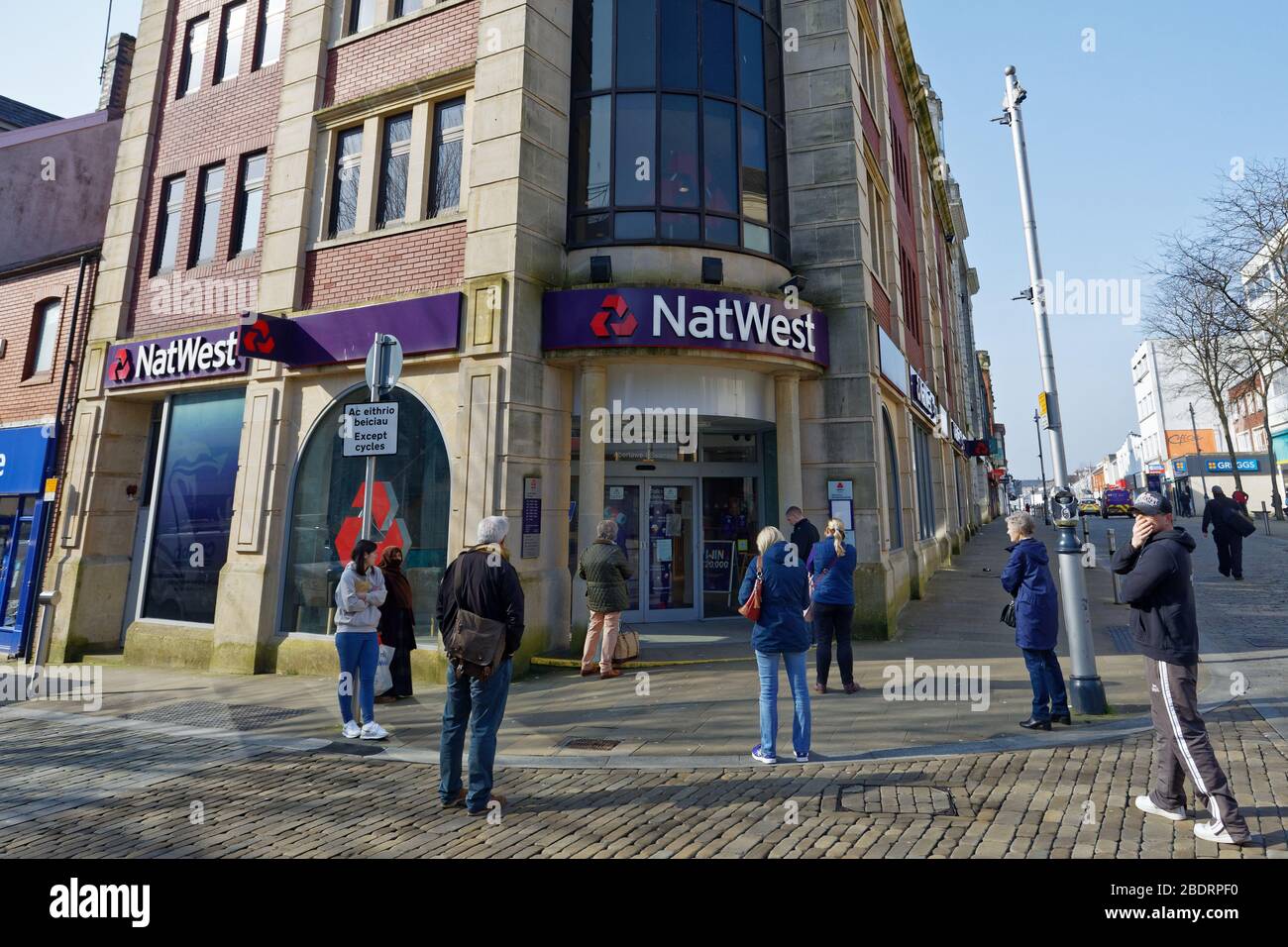 Im Bild: Eine Schlange von Kunden, die die Regeln der sozialen Distanzierung außerhalb der NatWest Bank in Oxford Street, Swansea, Wales, Großbritannien, beobachten. Dienstag, 24. März 2020 Re: Stockfoto