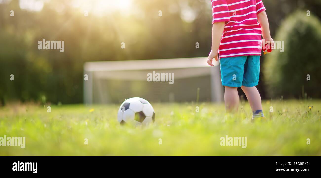 Kleiner Junge, der mit Toren Fußball auf dem Feld spielt Stockfoto