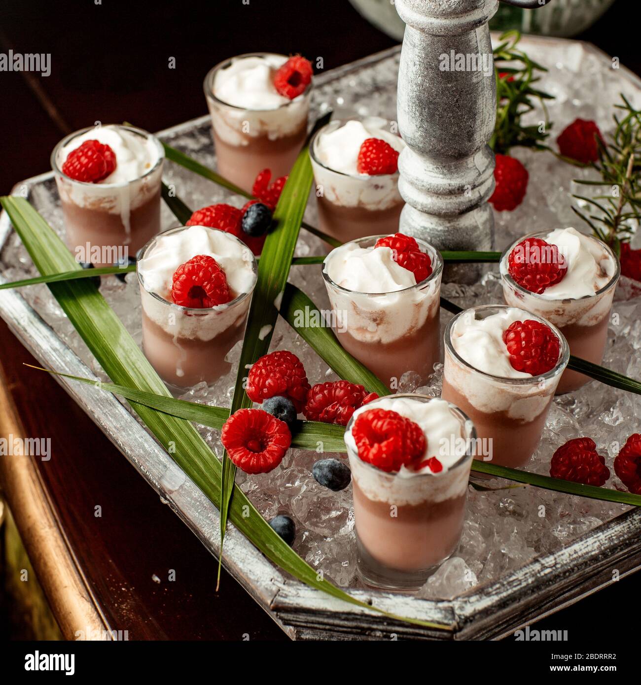 Schokoladenpudding mit Schlagsahne und Himbeere in Schnapsgläsern gekrönt Stockfoto