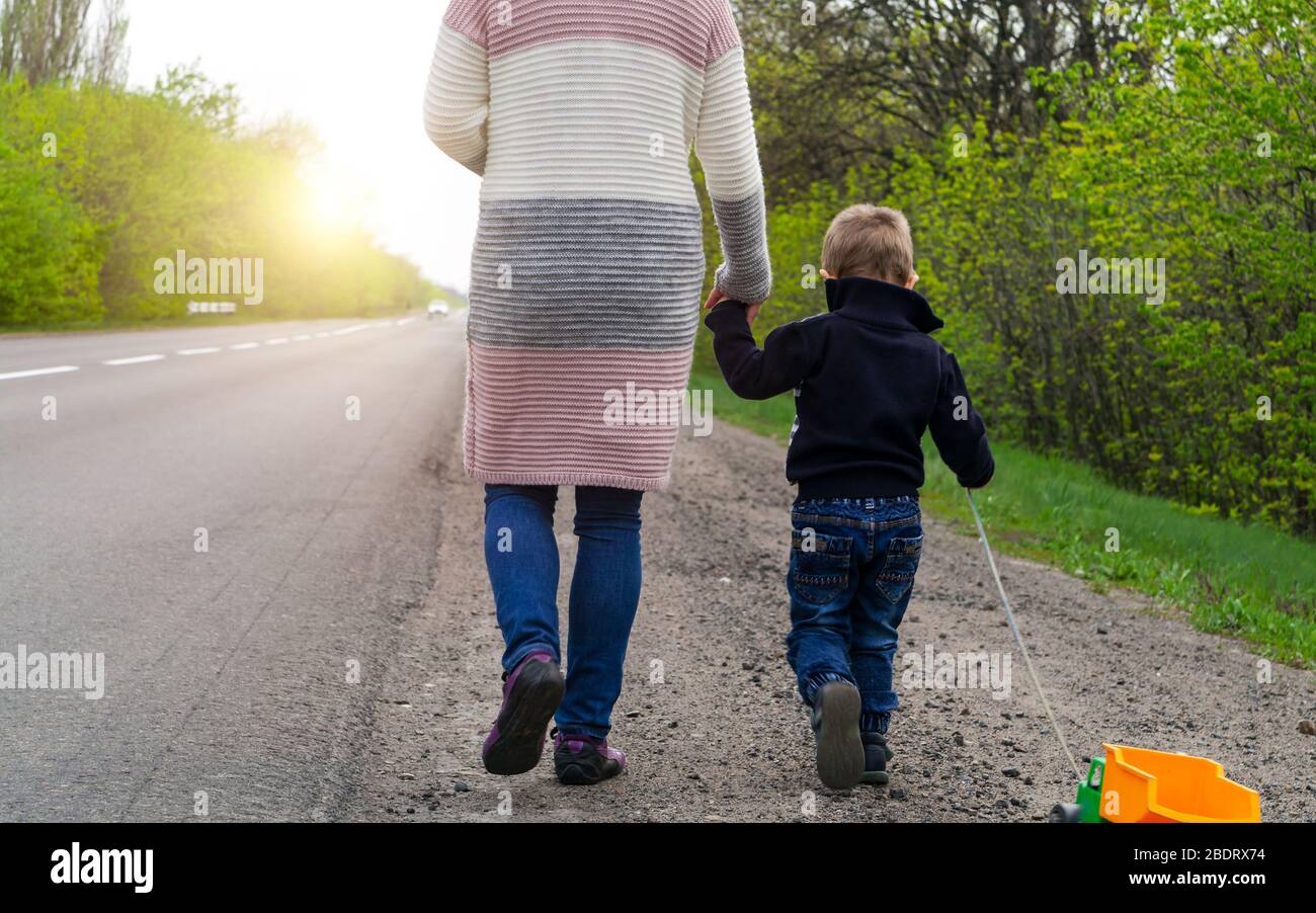 Morgenspaziergang. Das Kind mit seiner Mutter geht auf der Straße zum Sonnenaufgang. Stockfoto