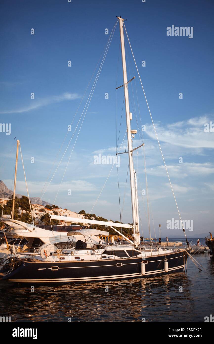 Segelyacht im Hafen einer kleinen Stadt, beleuchtet von der untergehenden Sonne. Vintage Toning Fotos Stockfoto