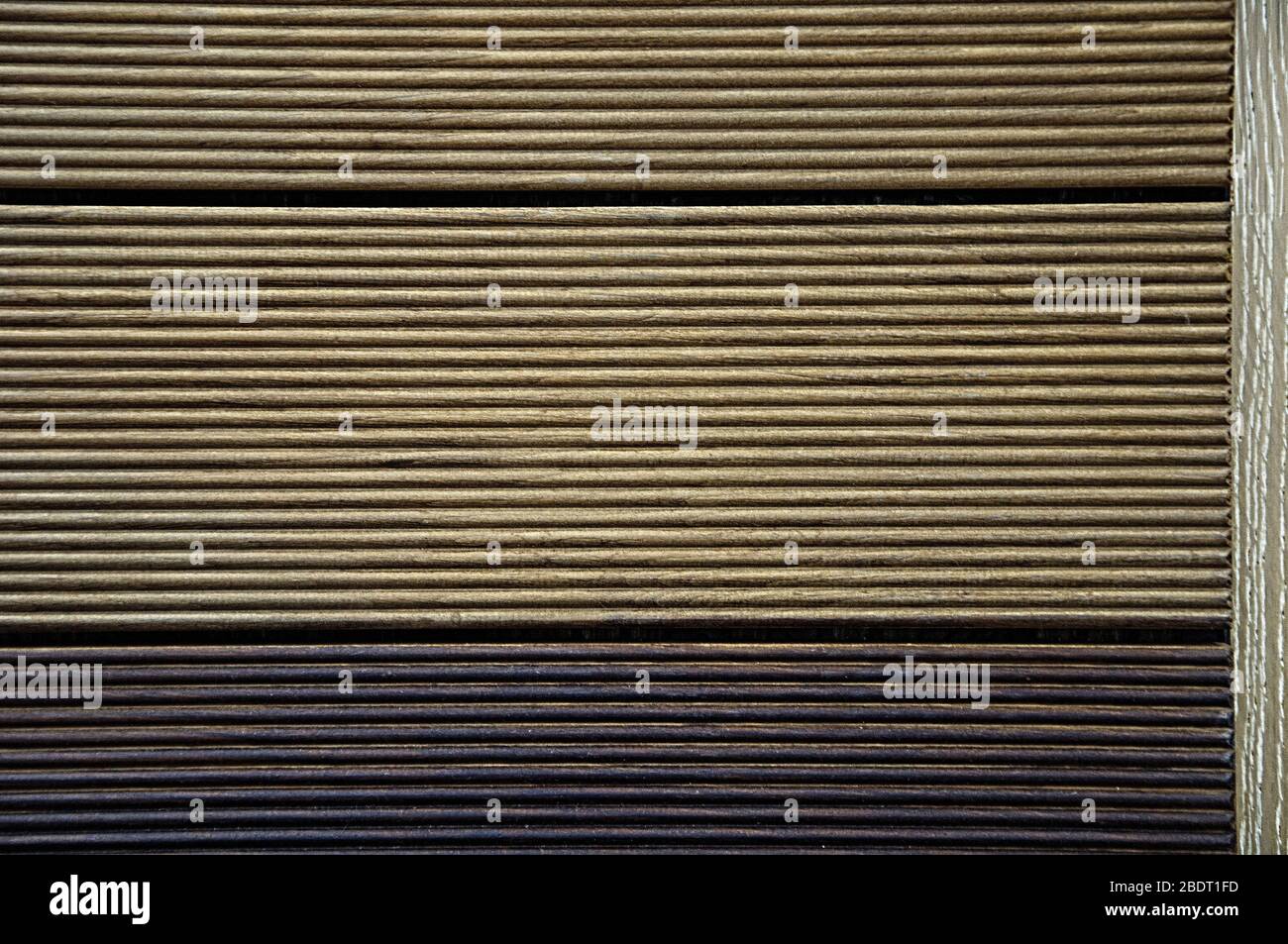 Ein Terrassenbrett mit Streifen. Holzstruktur. Hintergrund braun und schwarz. Stockfoto