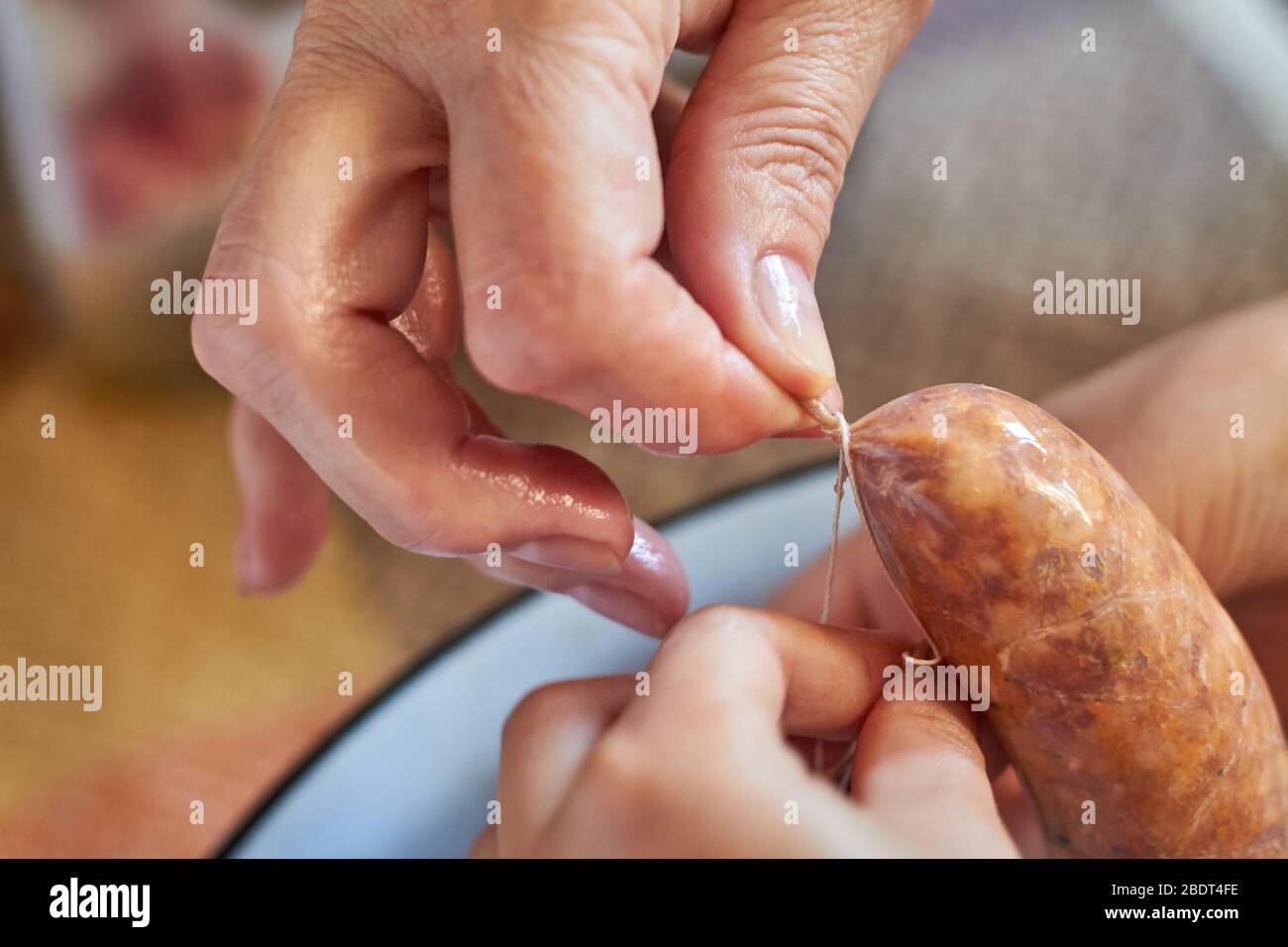 Eine Oma und ein Mädchen von Hand macht hausgemachte Wurst mit natürlichen Darm. Binden Sie einen Faden auf die Wurst.traditionelle Küche. Selektiver Fokus Stockfoto