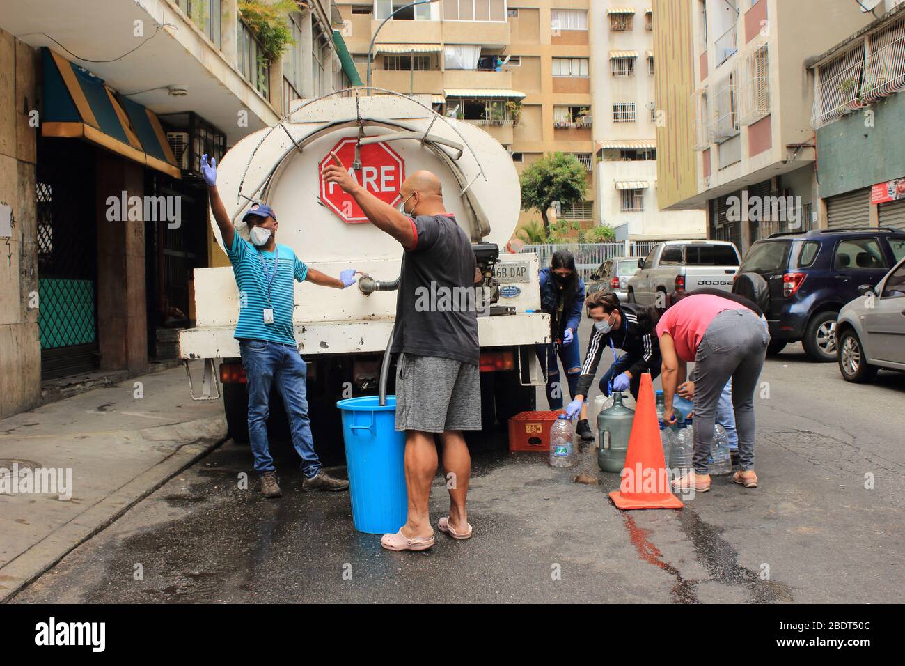 Caracas, Venezuela 4. April 2020: Menschen füllen Container mit Wasser aus LKW-Tanker Lieferung von großen Gemeinden während der COVID-19 Quarantäne Stockfoto