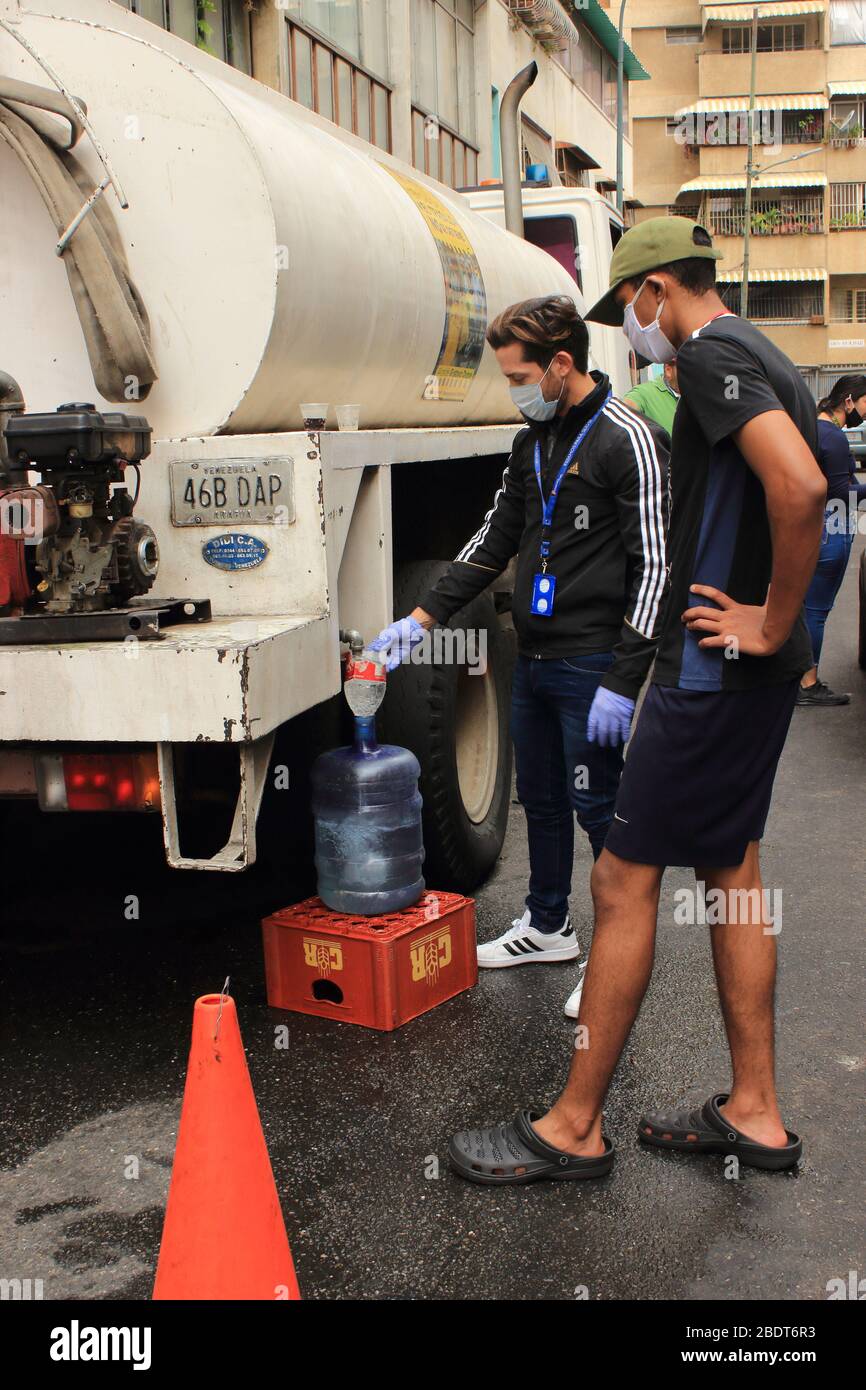 Caracas, Venezuela 4. April 2020: Menschen füllen Container mit Wasser aus LKW-Tanker Lieferung von großen Gemeinden während der COVID-19 Quarantäne Stockfoto
