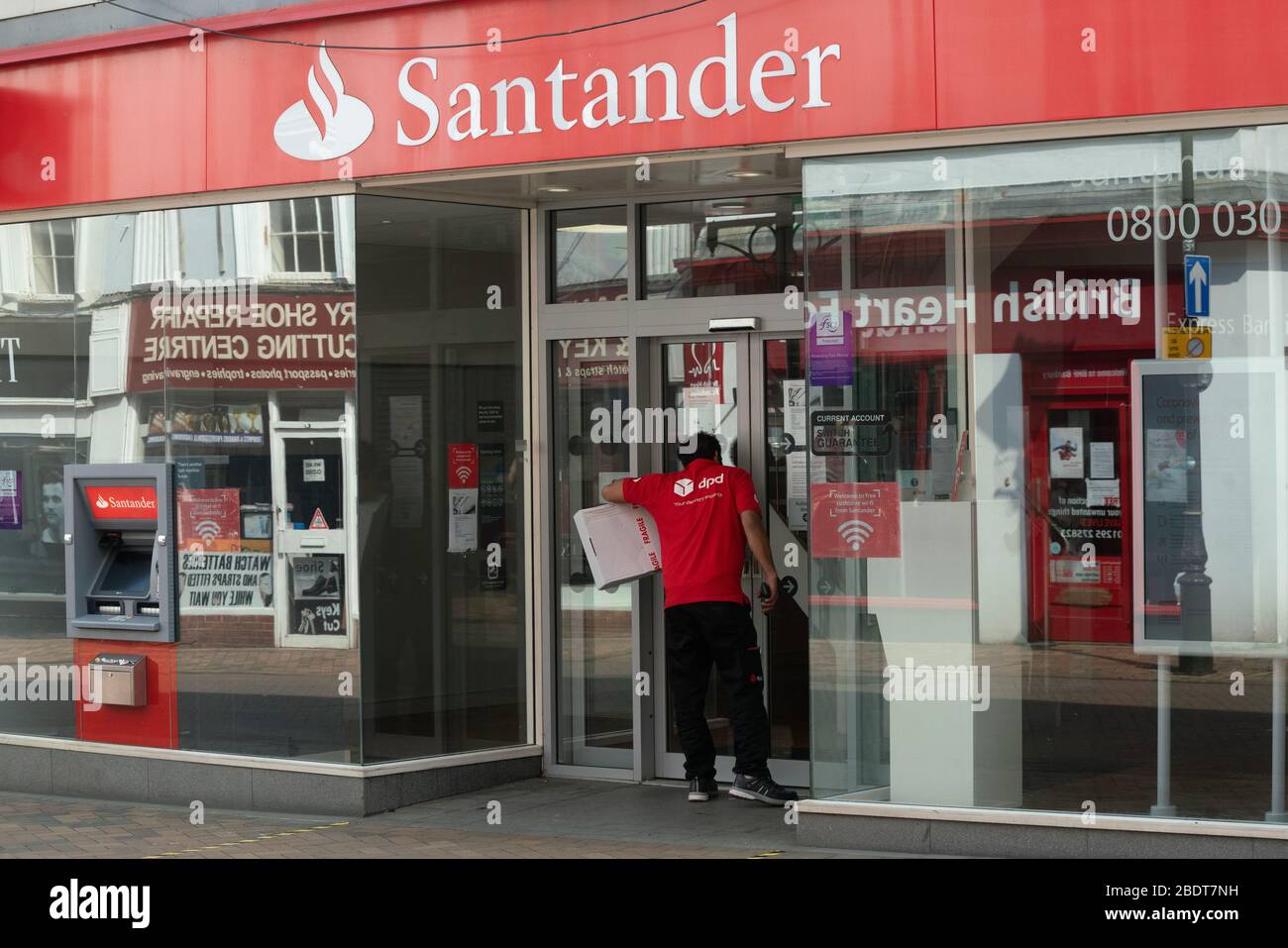 Ein Lieferfahrer wartet außerhalb der Santander Bank. Banken haben während der britischen Lockdown nur eingeschränkte Öffnungszeiten. Coronavirus. Stockfoto