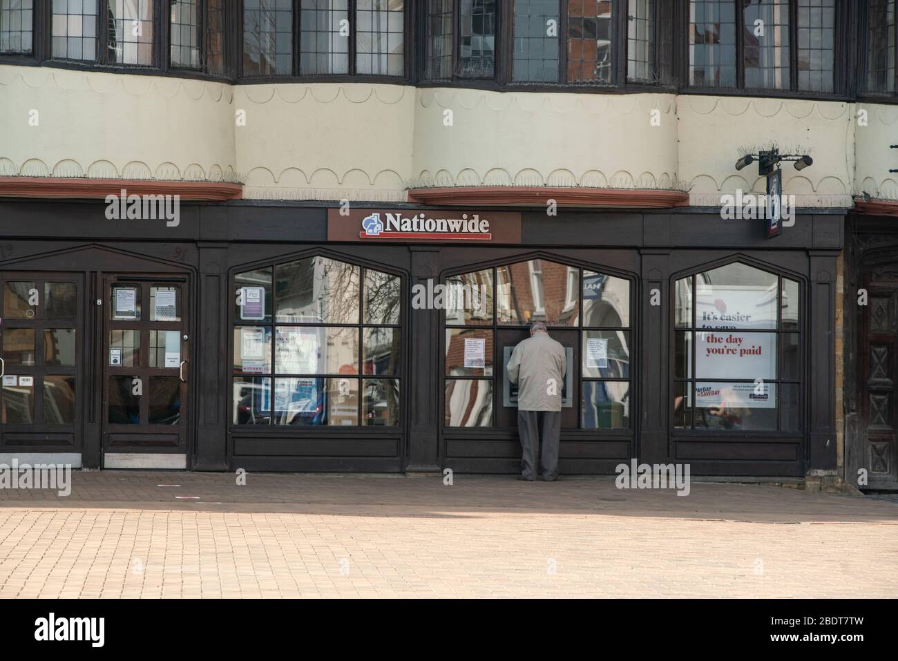 Während der Sperrung Großbritanniens steht ein Mann an einem landesweiten Geldautomaten auf einem verlassenen Marktplatz. Coronavirus. England Stockfoto