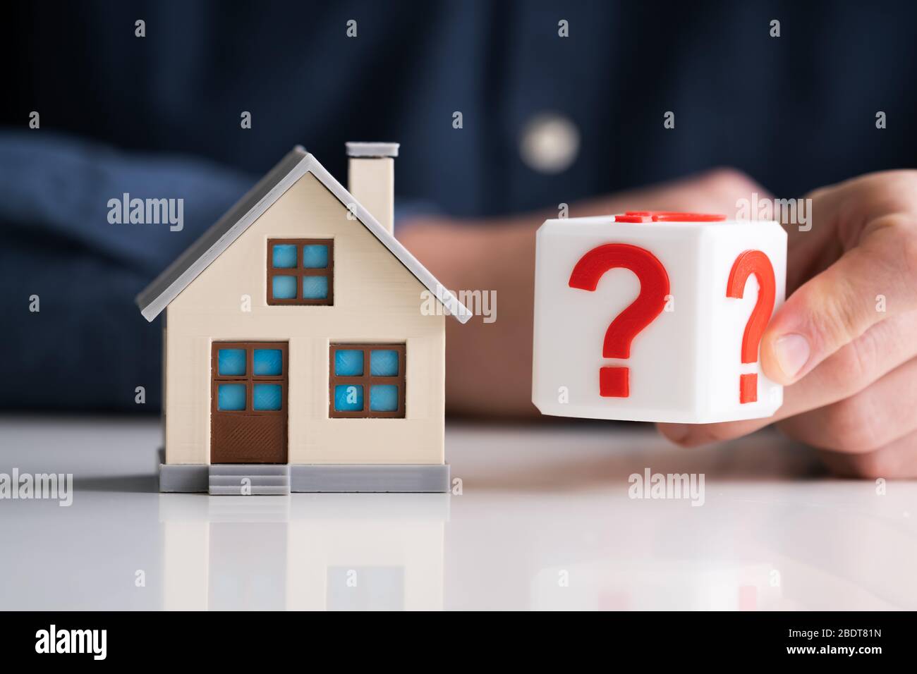 Man Holding Question Mark Cube Next To House Model Stockfoto