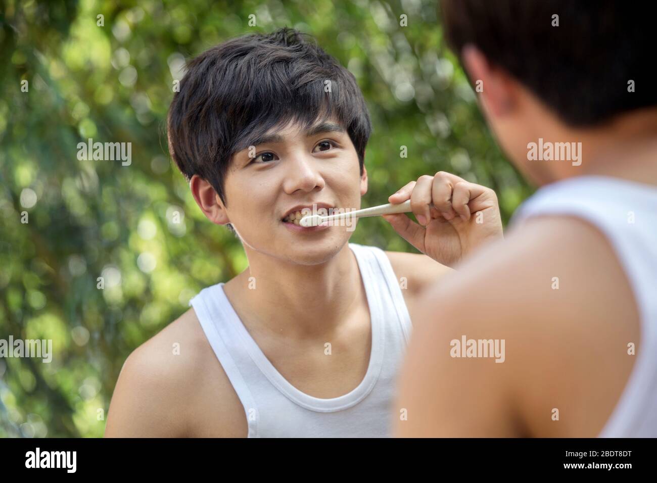 Draußen junger Mann putzt Ihre Zähne vor einem Spiegel Stockfoto