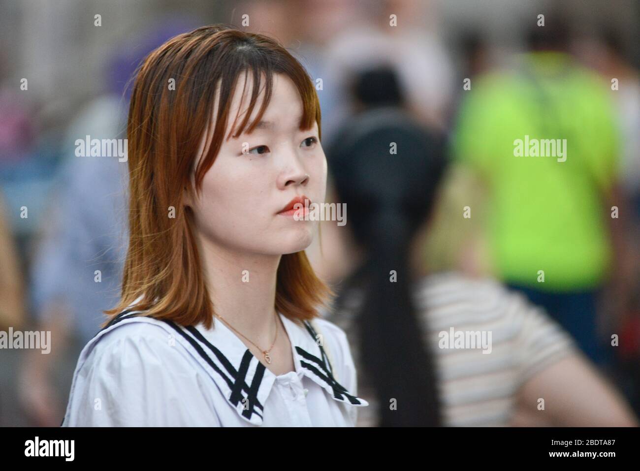 Chinesische junge Frau, die ernsthaft in der Jianghan Road, Wuhan, China aussieht Stockfoto