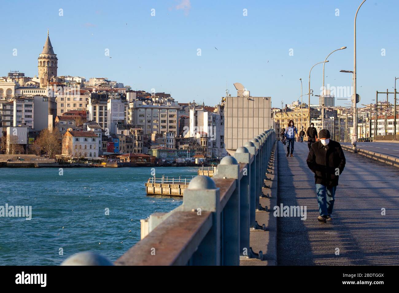 7. April 2020: Maskierte Bürger, die am 3. April 2020 auf der normalerweise recht überfüllten Galata-Brücke in der Nähe des Stadtteils Eminonu, Istanbul, TÜRKEI, spazieren gehen. Türkische Beamte haben die Bürger wiederholt aufgefordert, zu Hause zu bleiben und die sozialen Distanzierungsregeln zu respektieren. Die Türkei setzt weiterhin Maßnahmen zur Eindämmung der Verbreitung des Virus und zur Vermeidung einer vollständigen Sperrung ein, indem sie für alle Personen unter 60 Jahren und unter 20 Jahren Hausbestellungen ausgibt, Straßengrenzen von 31 Städten schließt, Bars schließt, Cafés und Restaurants und die Einschränkung öffentlicher Versammlungen.die Türkei bestätigte am 7. April 3.892 neue Coronavirus-Infektionen, Stockfoto