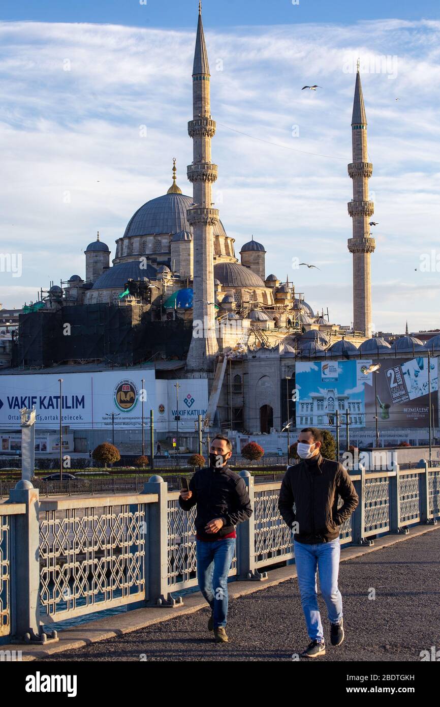 April 2020: Maskierte Bürger, die auf der normalerweise recht überfüllten Galatabrücke spazieren, mit neuer Moschee im Hintergrund, in der Nähe des Eminonu-Viertels, Istanbul, TÜRKEI, am 3. April 2020. Türkische Beamte haben die Bürger wiederholt aufgefordert, zu Hause zu bleiben und die sozialen Distanzierungsregeln zu respektieren. Die Türkei setzt weiterhin Maßnahmen zur Eindämmung der Verbreitung des Virus und zur Vermeidung einer vollständigen Sperrung ein, indem sie für alle Personen unter 60 Jahren und unter 20 Jahren Hausbestellungen ausgibt, Straßengrenzen von 31 Städten schließt, Bars schließt, Cafés und Restaurants und die Einschränkung öffentlicher Versammlungen.Türkei am 7. April bestätigt 3, Stockfoto