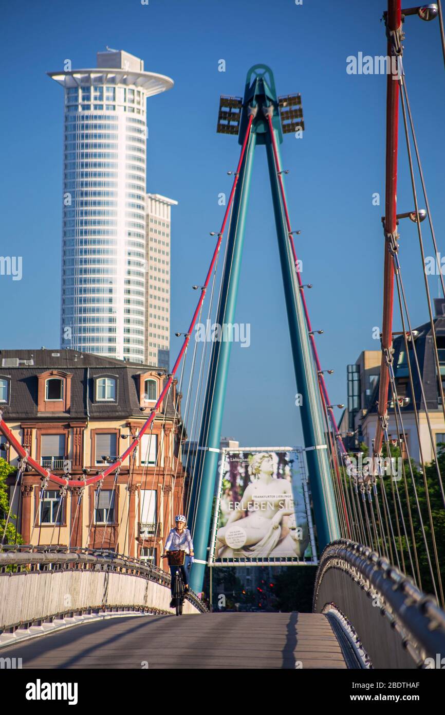 Ein einsamer Radfahrer Radfahren über Holbeinsteg Steg Bridge in der Dämmerung mit der Frankfurter Skyline der Stadt als Kulisse. Stockfoto