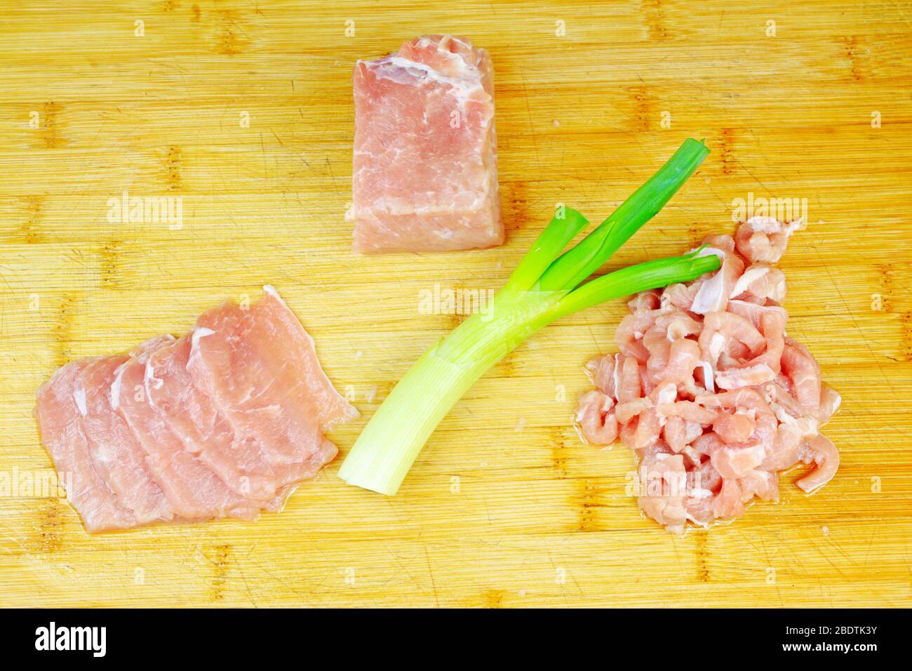 Mageres Fleisch, Zwiebeln und Knoblauch auf dem Schneidebrett Stockfoto