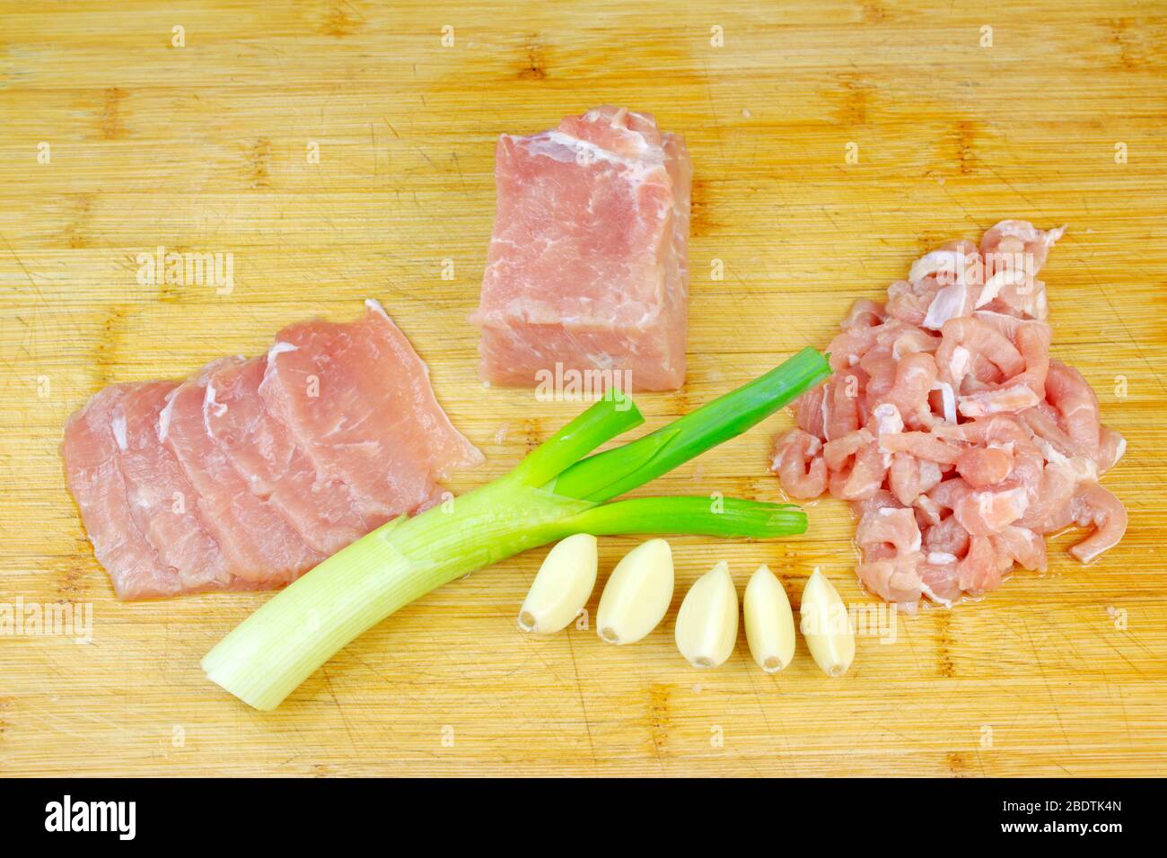 Mageres Fleisch, Zwiebeln und Knoblauch auf dem Schneidebrett Stockfoto