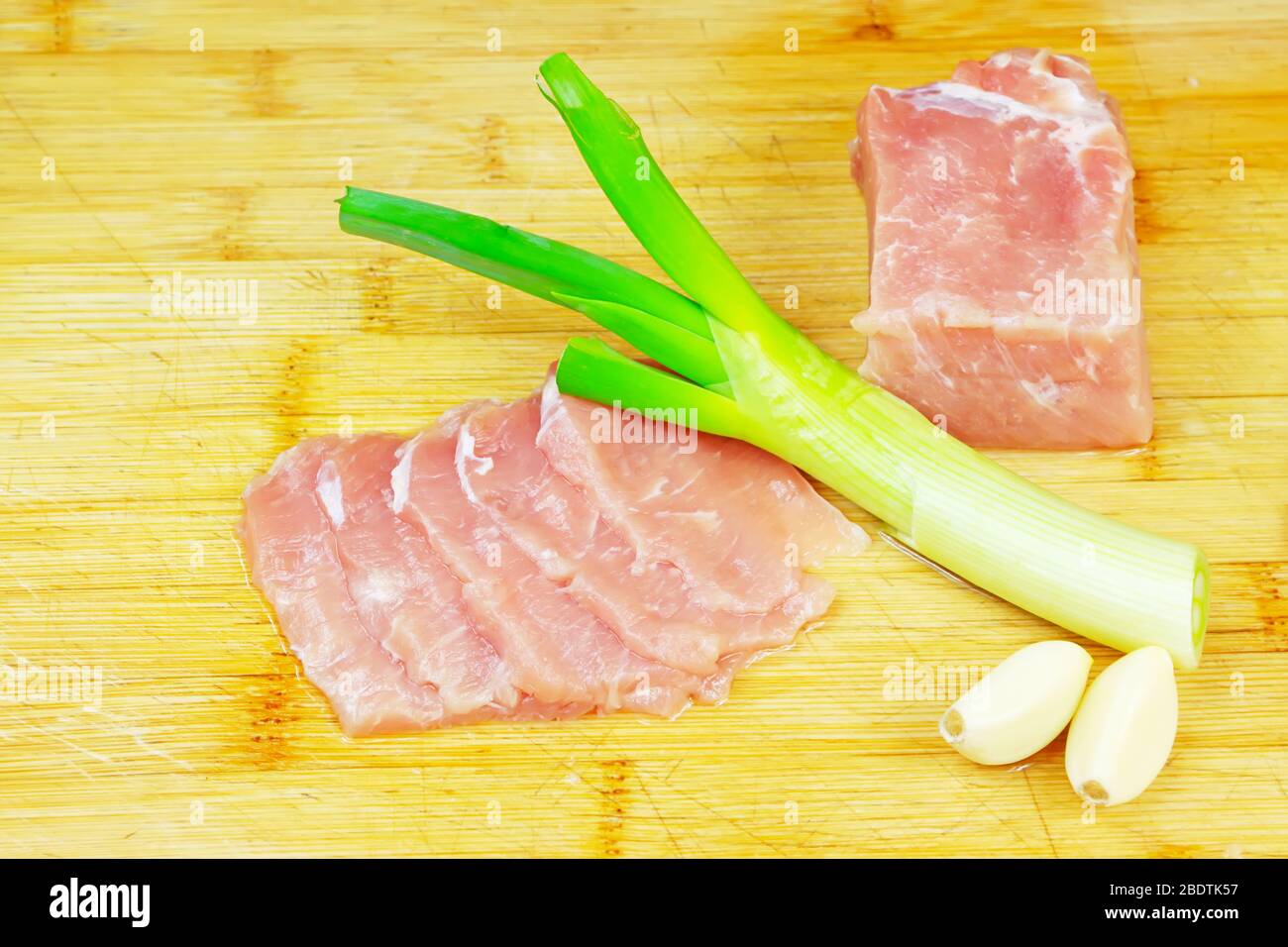 Mageres Fleisch, Zwiebeln und Knoblauch auf dem Schneidebrett Stockfoto