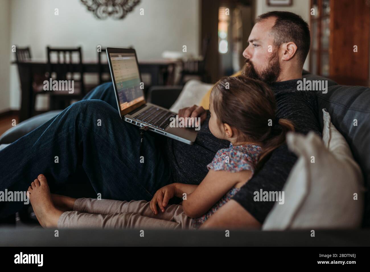 Vater arbeitet von zu Hause mit jungen Tochter während der Isolation Stockfoto