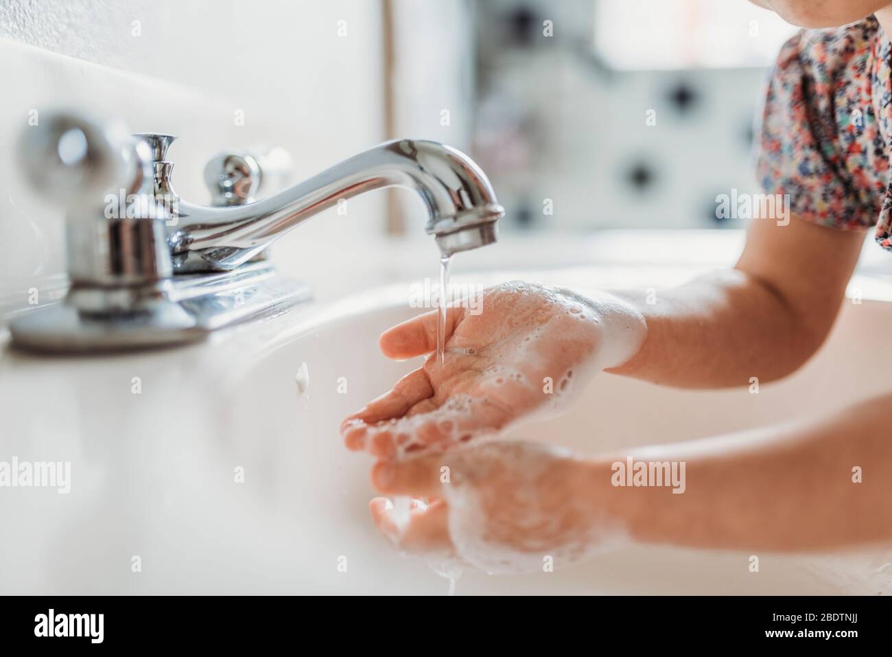 Nahaufnahme des kleinen Kindes, das die Hände mit Seife im Waschbecken wäscht Stockfoto