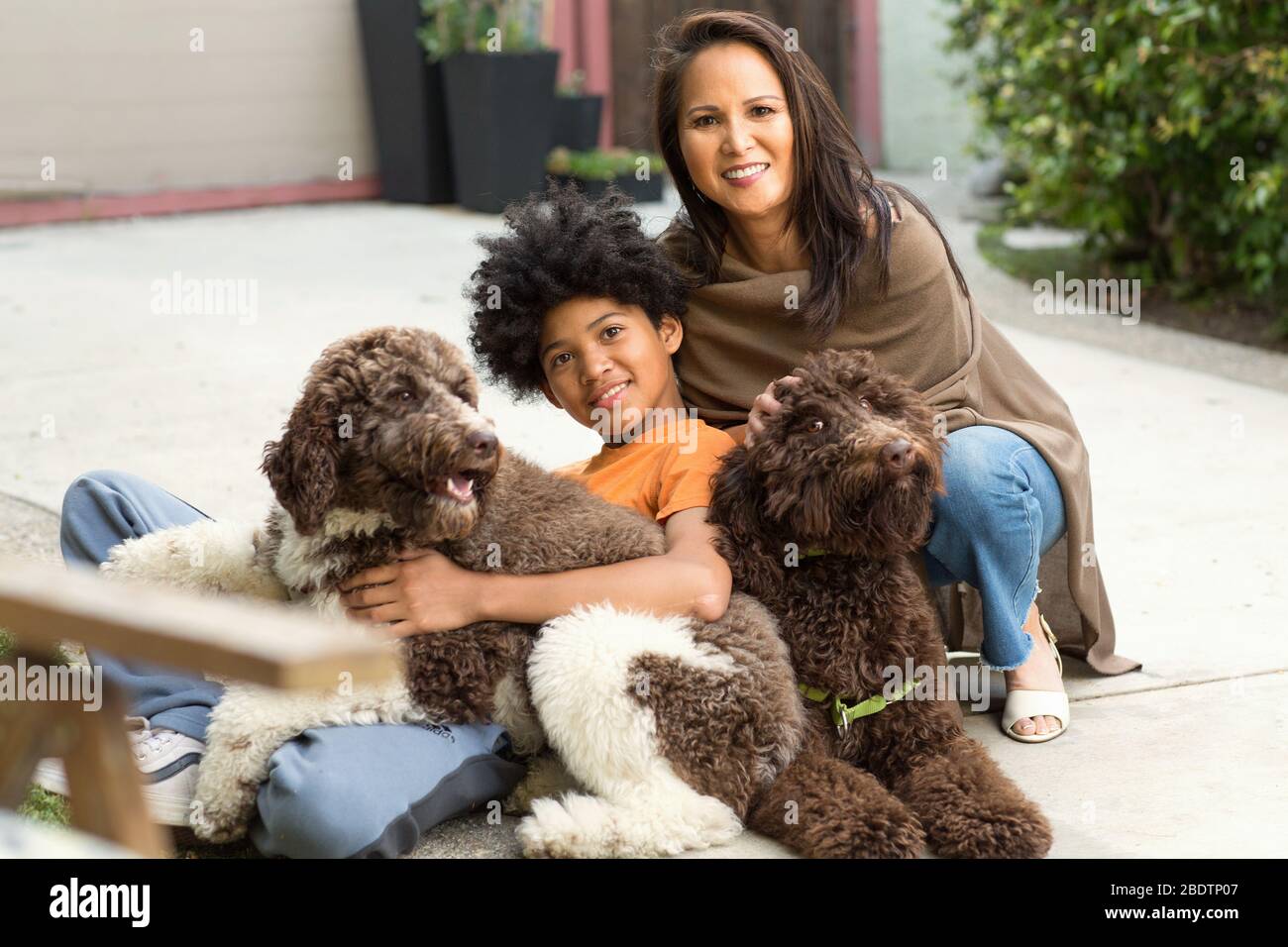 Mutter und ihr Sohn lachen und spielen mit ihrem Hund. Stockfoto
