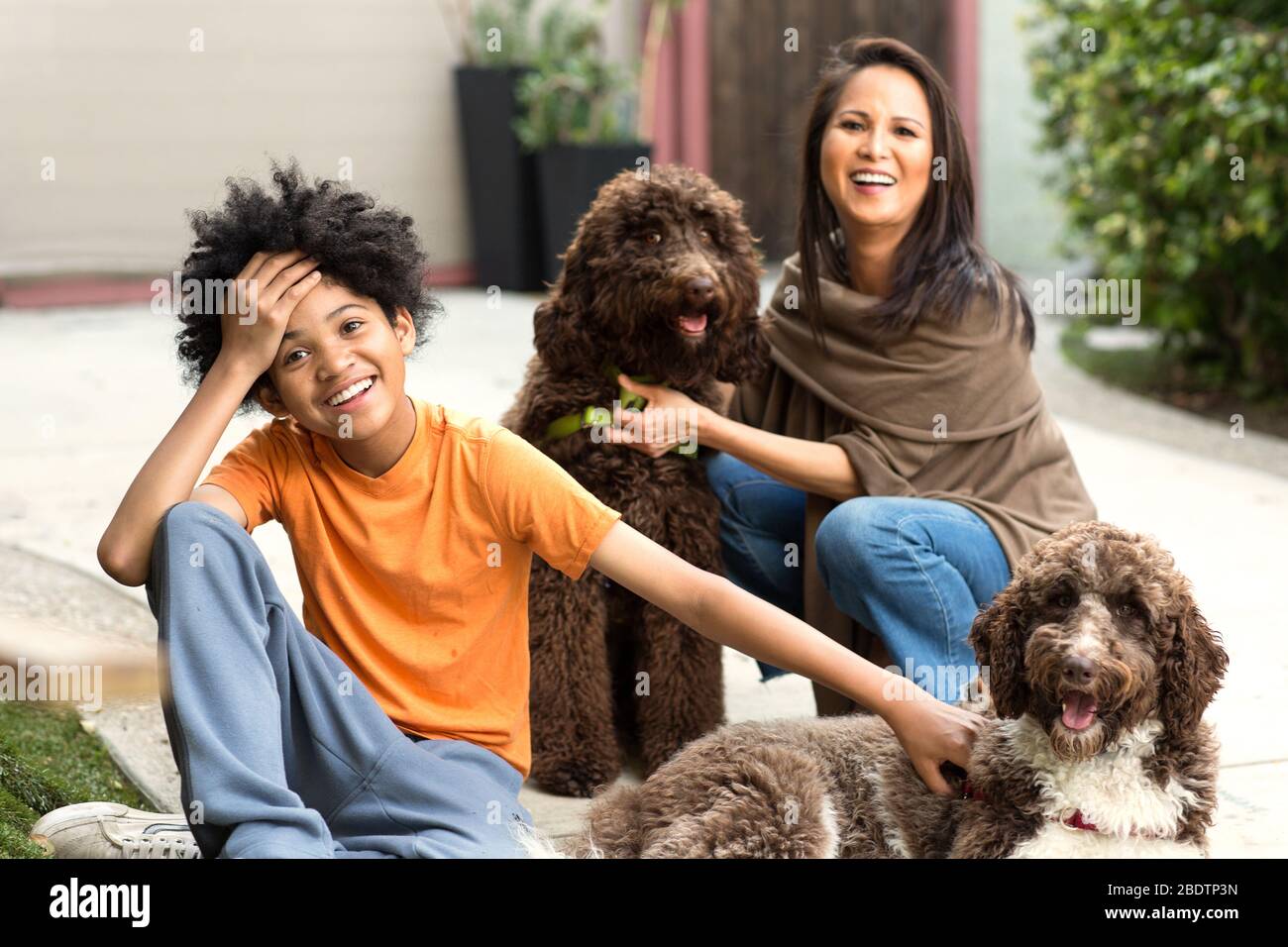 Mutter und ihr Sohn lachen und spielen mit ihrem Hund. Stockfoto