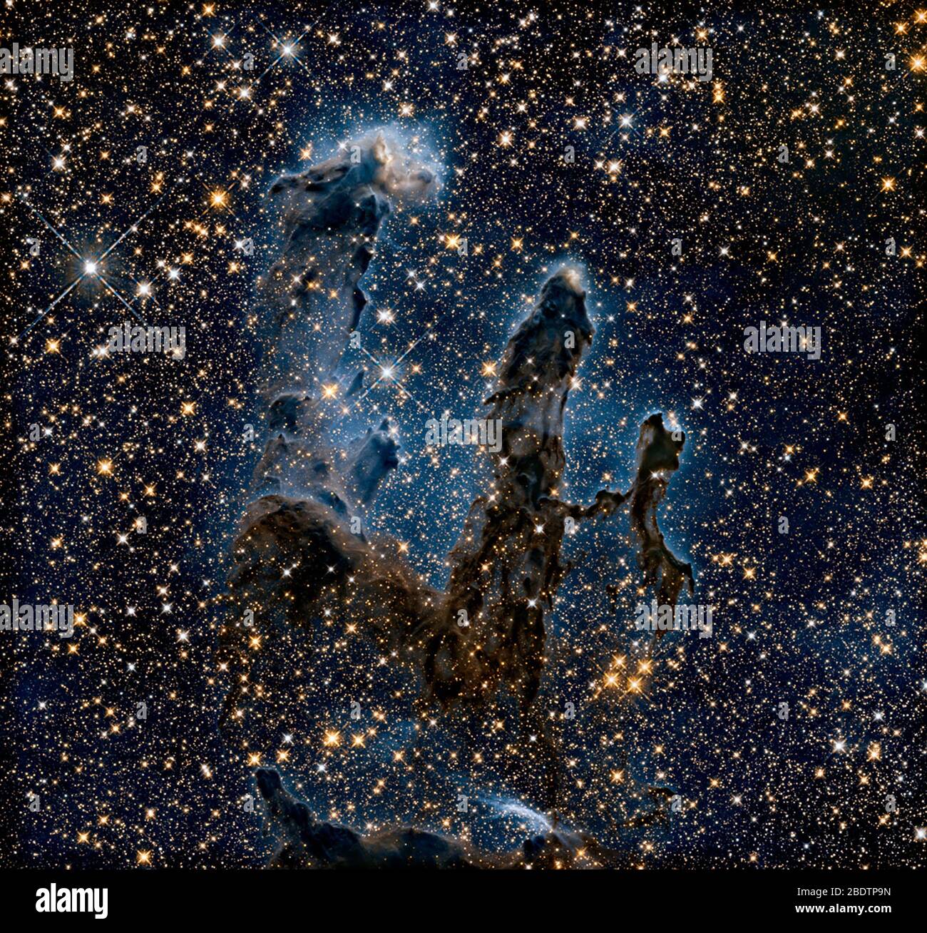 Das NASA/ESA Hubble Space Telescope hat eines seiner ikonischen und beliebtesten Bilder erneut besucht: Die Säulen der Schöpfung des Adler-Nebels. Dieses Bild zeigt die Säulen, wie sie im Infrarotlicht zu sehen sind, und ermöglicht es, Staub und Gas zu durchstechen und eine ungewohnte, aber ebenso erstaunliche Sicht auf die Säulen zu enthüllen. In dieser ätherischen Ansicht ist der gesamte Rahmen mit hellen Sternen gespickt, und es werden Babysterne innerhalb der Säulen selbst gebildet. Die gespenstischen Umrisse der Säulen wirken viel zierlicher und sind gegen einen unheimlichen blauen Dunst silhouettiert. Hubble erfasste auch die Säulen Stockfoto