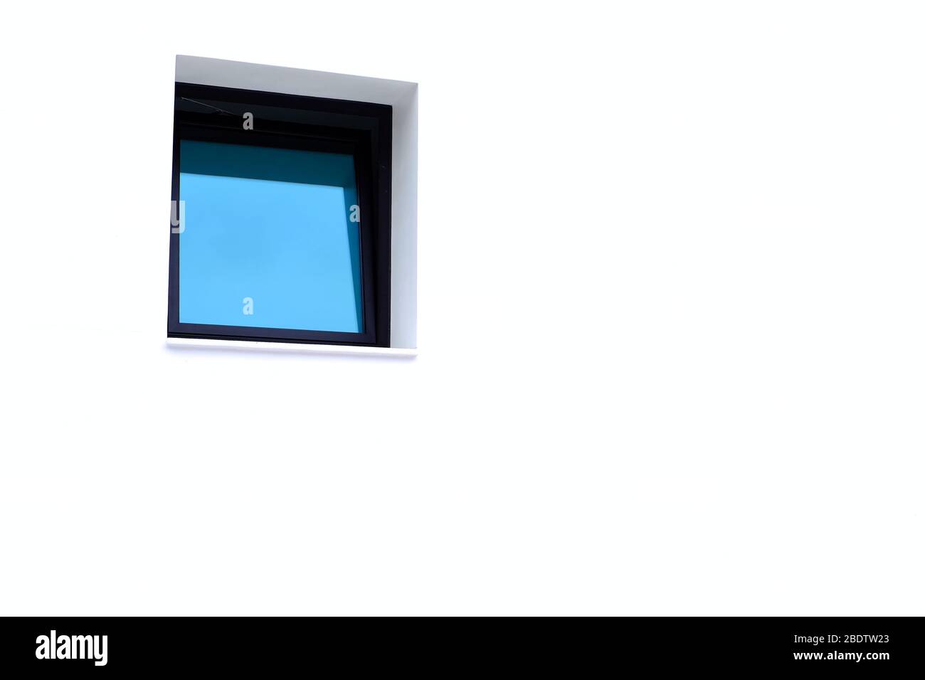 Ein einzelnes blaues Fenster in einer hellen weißen Wand, großer Text-/Textraum. Stockfoto