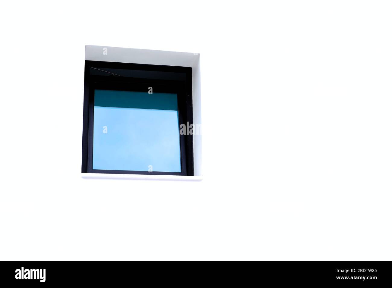 Ein dunkles Fenster in einer hellen weißen Wand, großer Text-/Textraum. Stockfoto