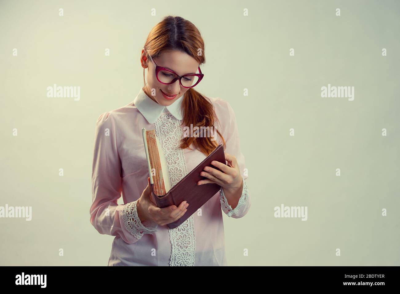Eine junge hübsche Frau zwischen 30 und 40 Jahren mit einem alten Buch. Freier Platz für Textanzeigen Stockfoto