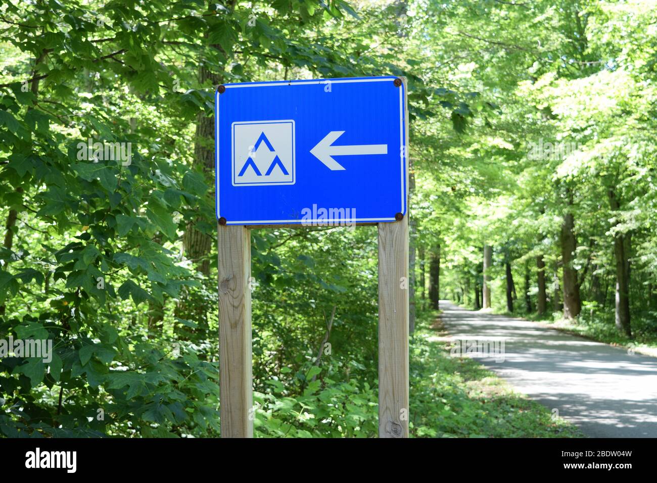 Blaues Schild mit Wegbeschreibung zu Zeltplätzen auf einem Campingplatz. Wanderweg im Hintergrund. Natururlaub mit Familie und Freunden. Stockfoto