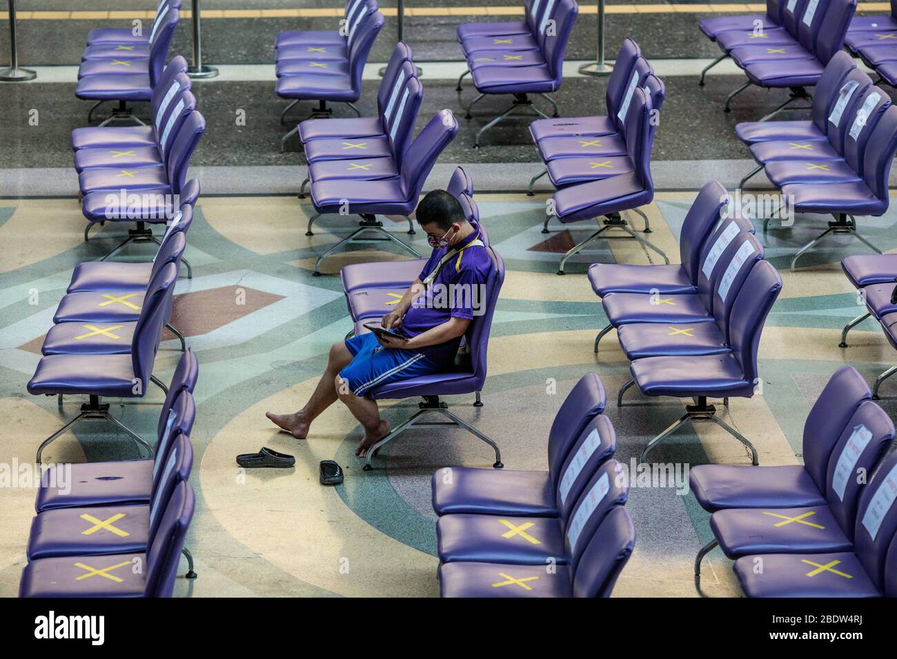 BANGKOK, THAILAND: Ein Mann sitzt allein in einem Wartebereich in Hua Lamphong, Bangkok Railway Station, wo Stühle mit XS markiert wurden, damit Menschen inmitten der COVID-19 Coronavirus Ängste am 6. April 2020 in Thailand soziale Distanz üben können. Stockfoto