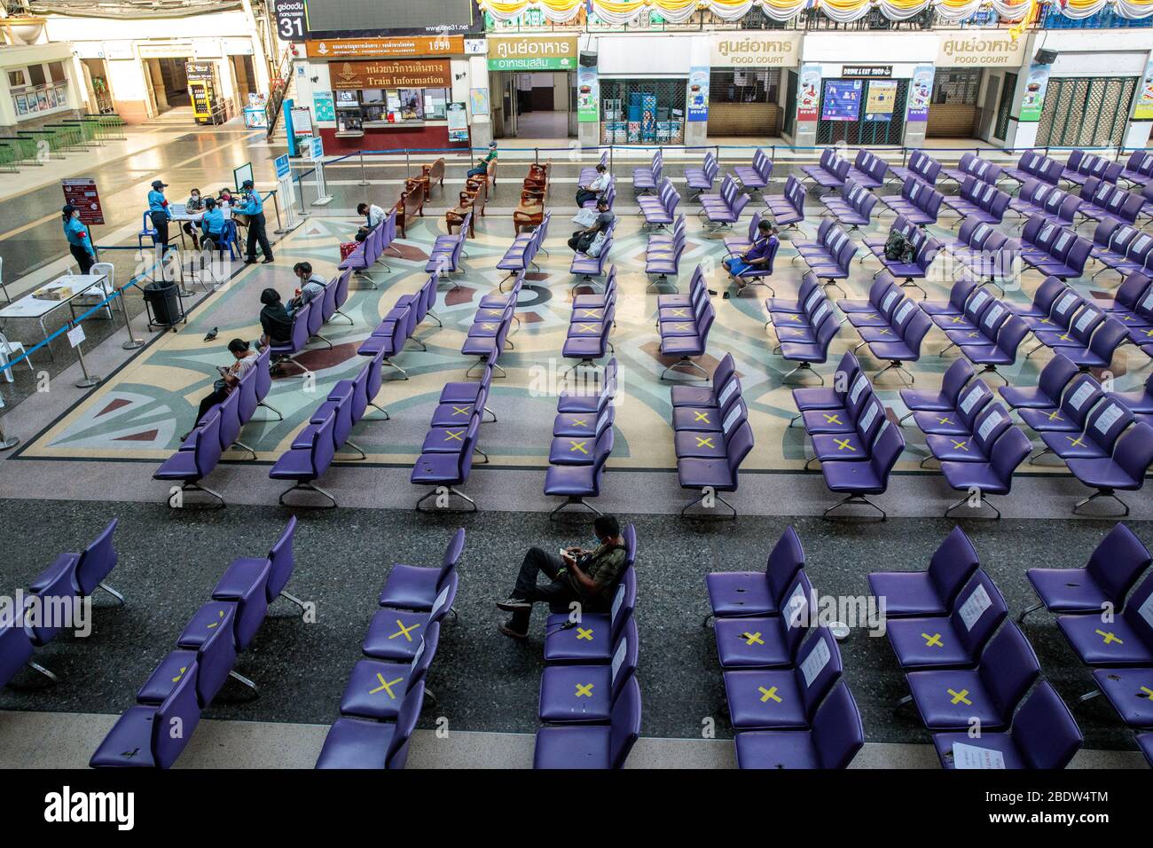 BANGKOK, THAILAND: Ein Mann sitzt allein in einem Wartebereich in Hua Lamphong, Bangkok Railway Station, wo Stühle mit XS markiert wurden, damit Menschen inmitten der COVID-19 Coronavirus Ängste am 6. April 2020 in Thailand soziale Distanz üben können. Stockfoto