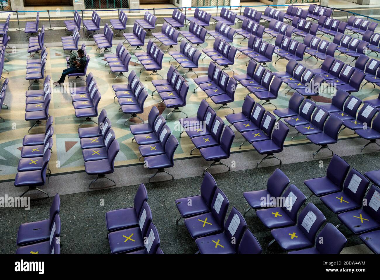 BANGKOK, THAILAND: Ein Mann sitzt allein in einem Wartebereich in Hua Lamphong, Bangkok Railway Station, wo Stühle mit XS markiert wurden, damit Menschen inmitten der COVID-19 Coronavirus Ängste am 6. April 2020 in Thailand soziale Distanz üben können. Stockfoto
