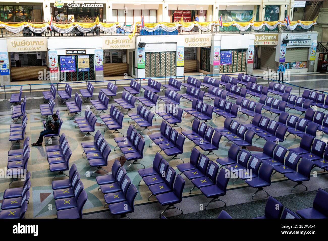 BANGKOK, THAILAND: Ein Mann sitzt allein in einem Wartebereich in Hua Lamphong, Bangkok Railway Station, wo Stühle mit XS markiert wurden, damit Menschen inmitten der COVID-19 Coronavirus Ängste am 6. April 2020 in Thailand soziale Distanz üben können. Stockfoto
