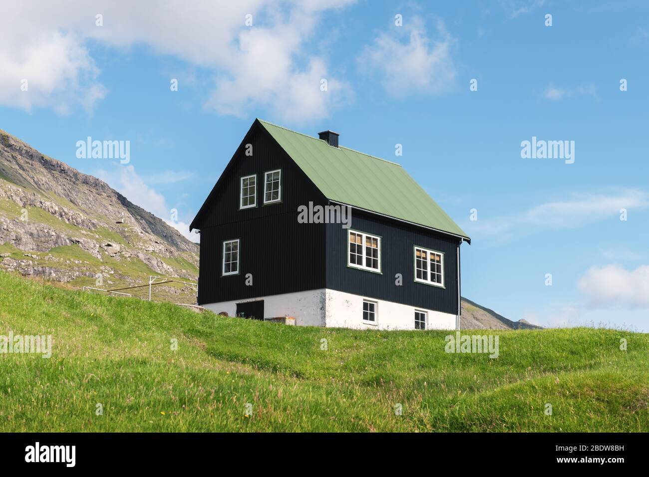 Einfaches Haus mit grünem Dach auf blauem Himmel Hintergrund Stockfoto