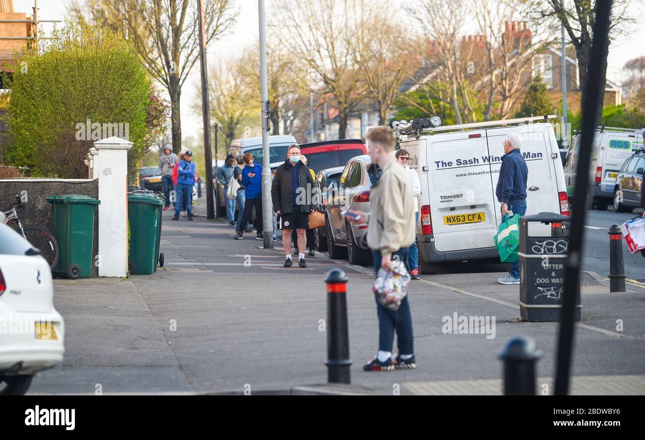 Brighton UK 10. April 2020 - die Käufer stehen am Karfreitagmorgen früh in der Ravens Bakery in Brighton an, wo sie für ihre heißen Brötchen berühmt sind. Die Regierung hat der Öffentlichkeit gesagt, während des Coronavirus COVID-19 Pandemiekrise am Osterwochenende nicht zu gehen. Quelle: Simon Dack / Alamy Live News Stockfoto