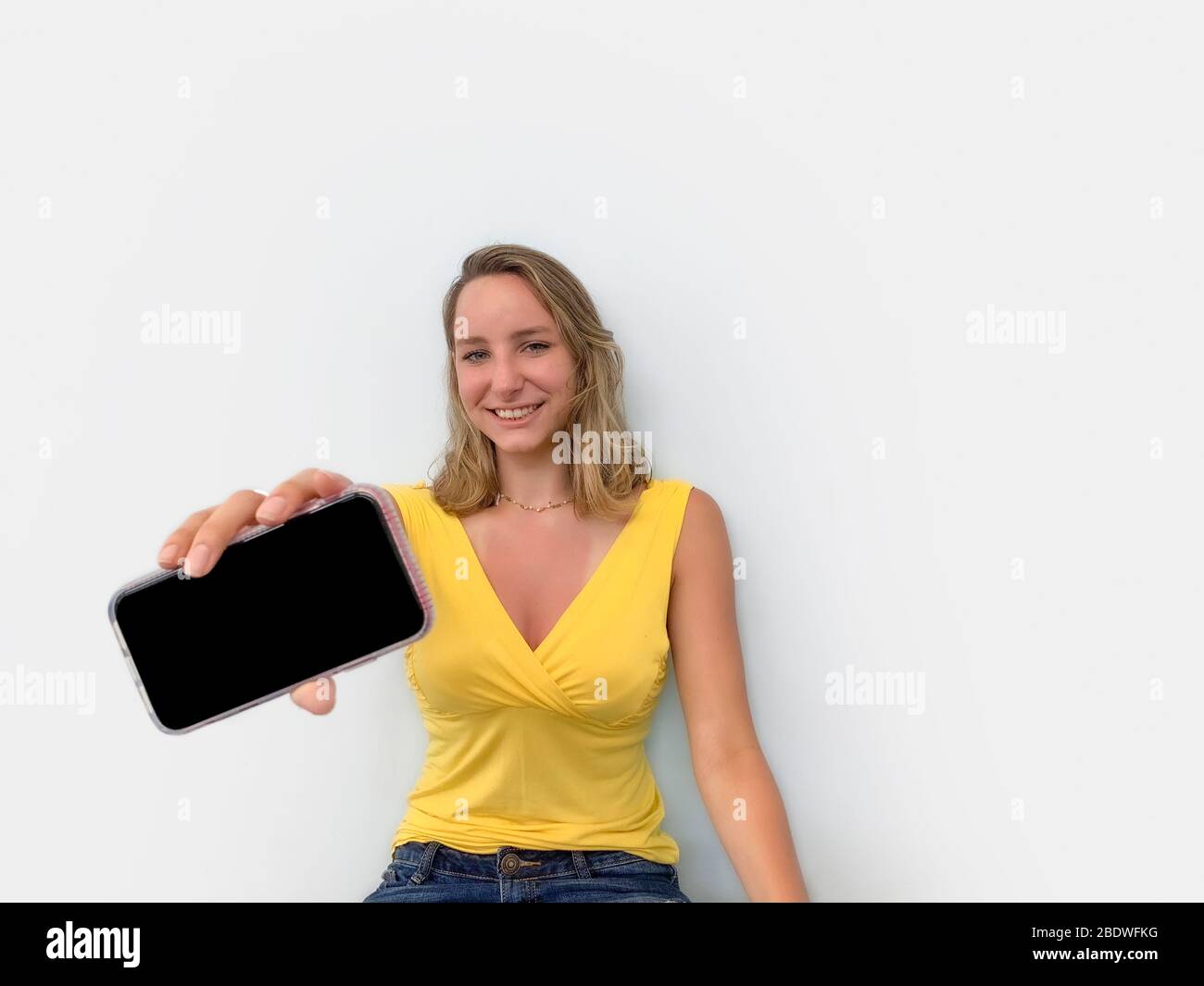 Junge Frau präsentiert ein Smartphone Stockfoto