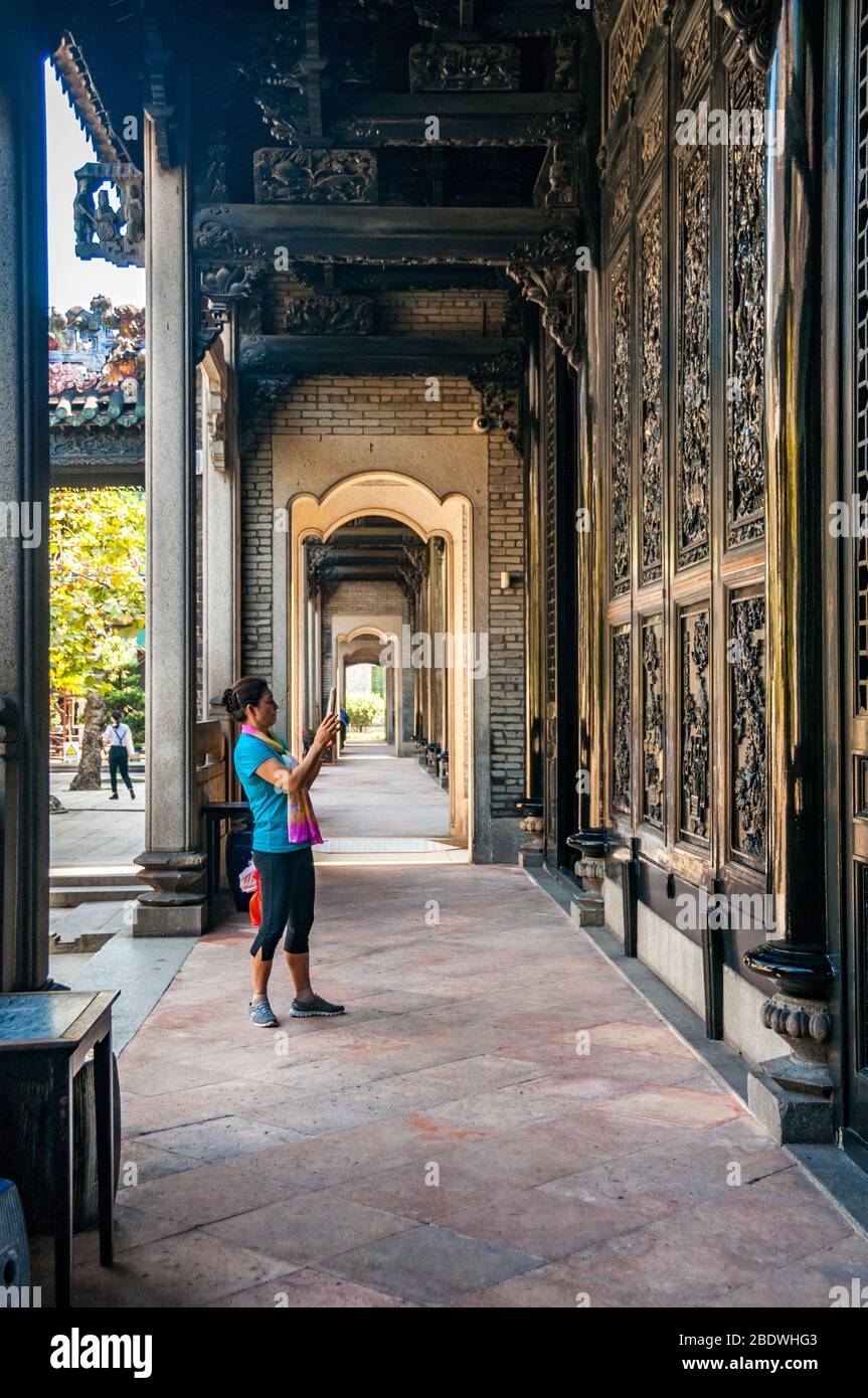 Ein Tourist fotografiert geschnitzte Holztafeln an der Seite eines Gebäudes an der Chen Clan Akademie, Guangzhou, China Stockfoto