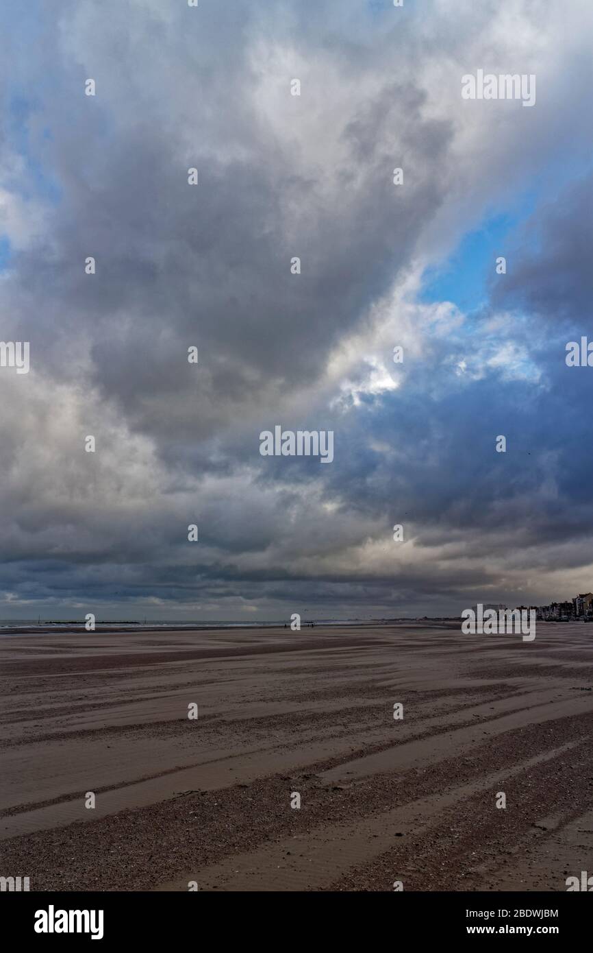 Dünkirchen Beach und Sea Front mit Menschen, die unter einem dramatischen Himmel an einem windigen Novembermorgen entlang laufen. Stockfoto