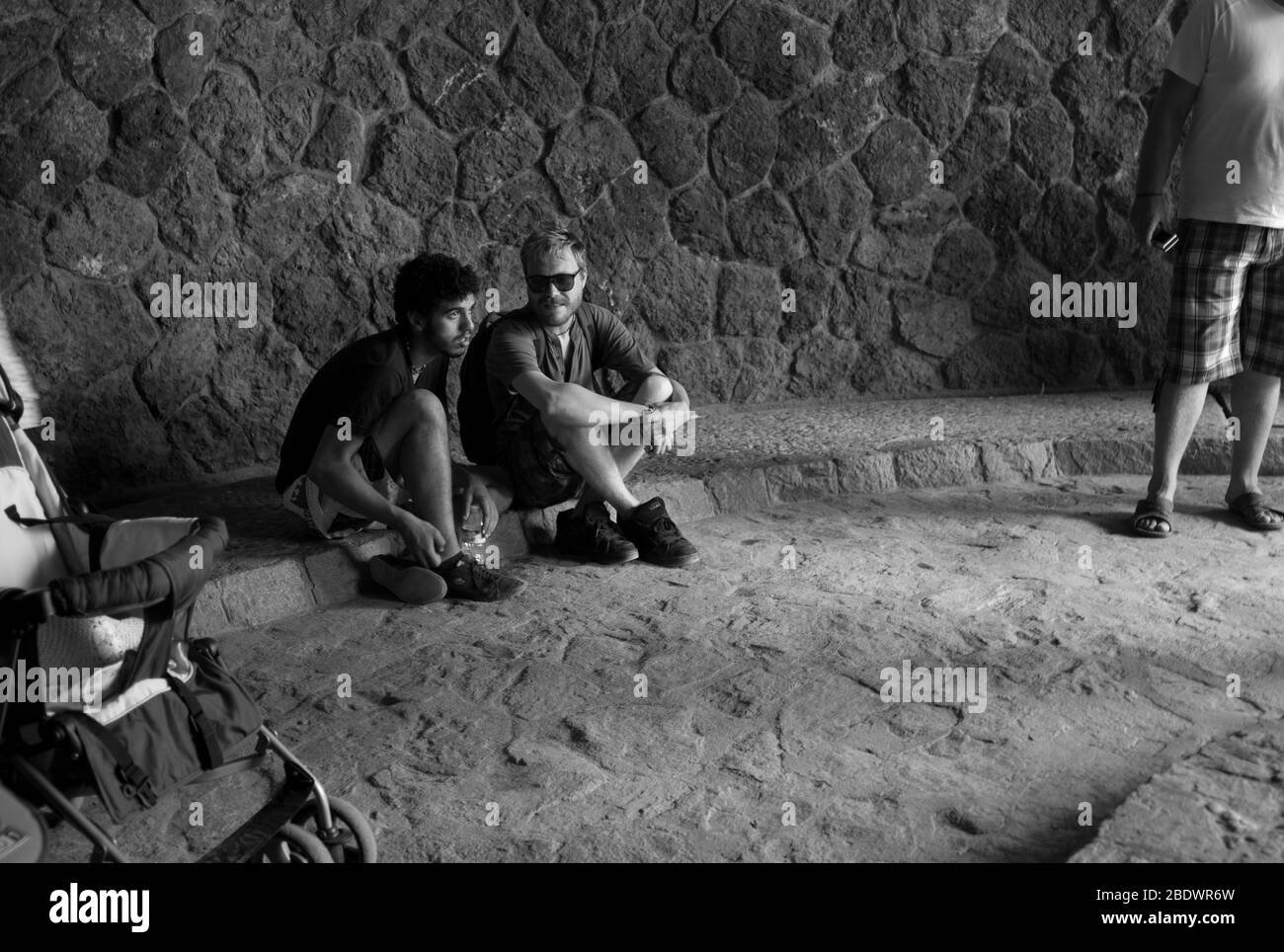 Touristen sitzen in Steinhöhlenanlage, Park Güell, Barcelona Stockfoto