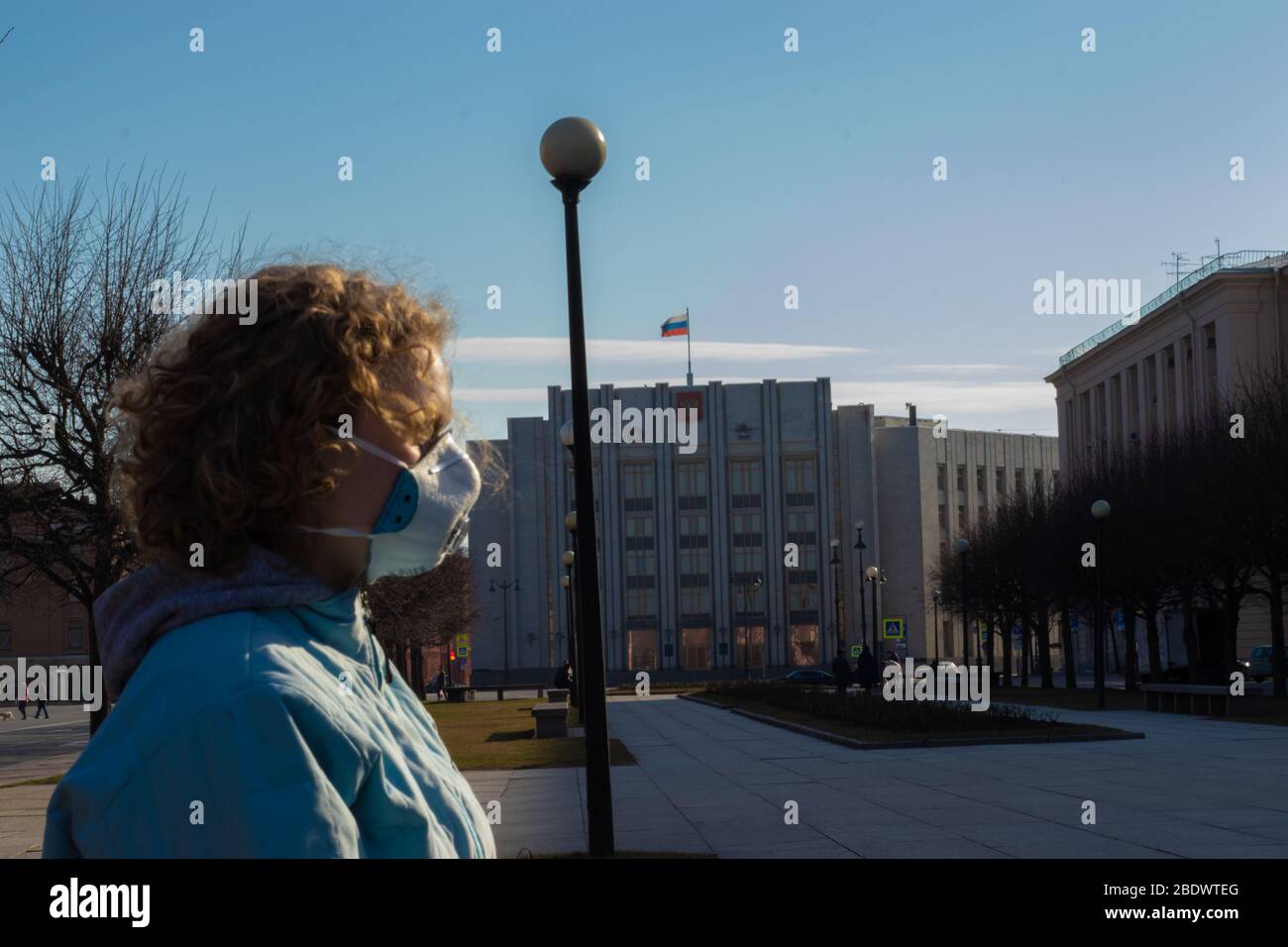 Sankt Petersburg, Russland - 28. März 2020: Frau auf der Straße in Gesichtsschutzmaske mit russischer Flagge auf Hintergrund, illustrative Editorial Stockfoto