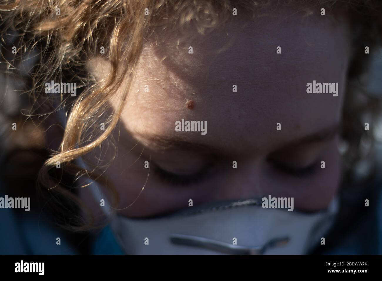 Nahaufnahme von jungen Mädchen Gesicht in medizinischen Atemschutzmaske. Nahaufnahme von Augen im Schatten Stockfoto