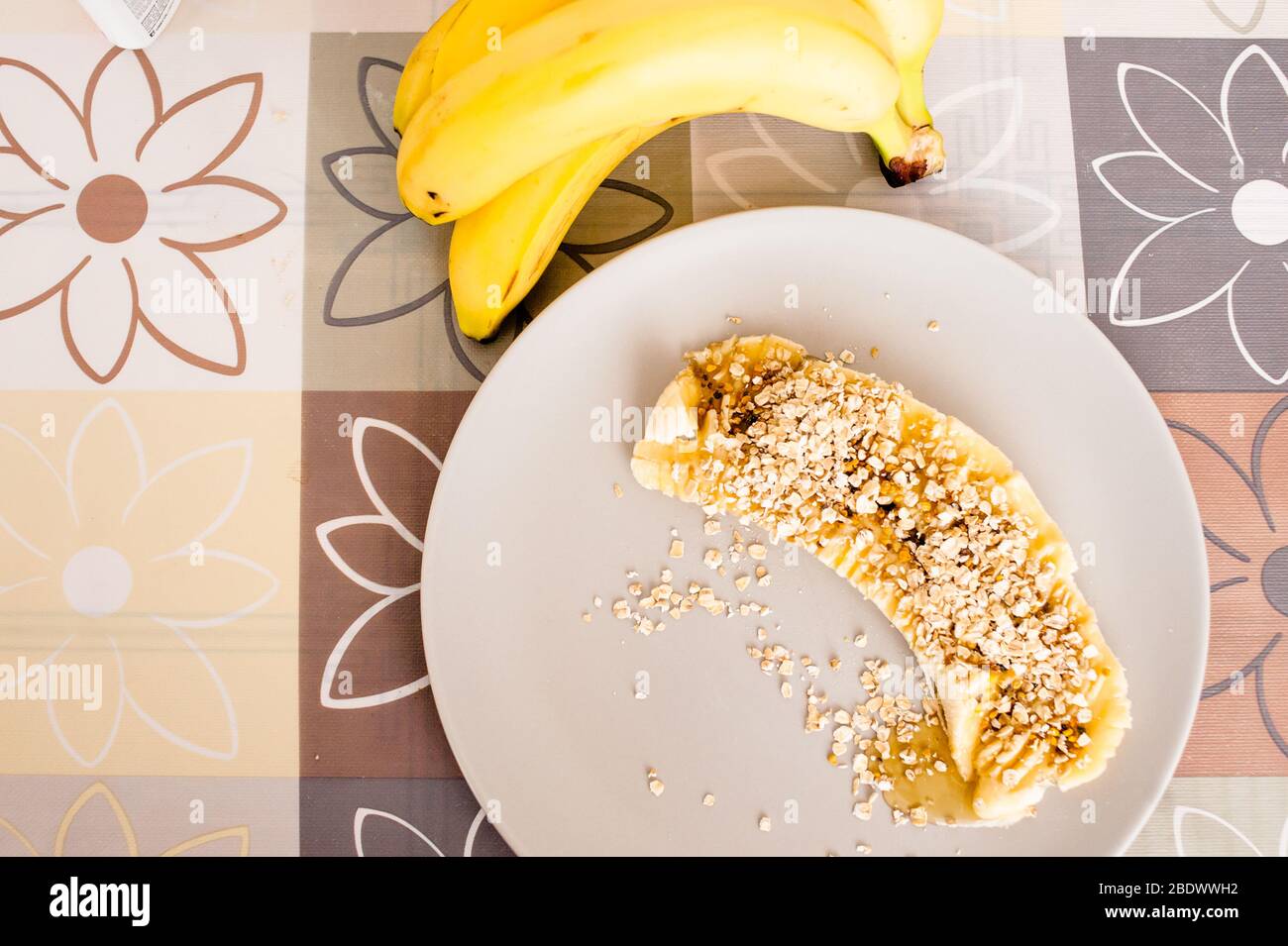Hohe Winkelansicht einer Banane in Scheiben, die mit Hafer und Honig bedeckt ist. Stockfoto