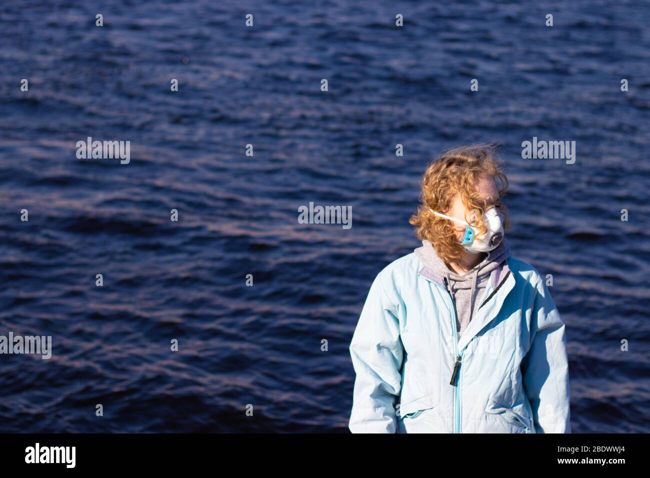 Mädchen in schützende Gesichtsmaske schaut weg auf einem Wasser Hintergrund. Speicherplatz für Gesundheitsprobleme und Virenkonzept kopieren Stockfoto