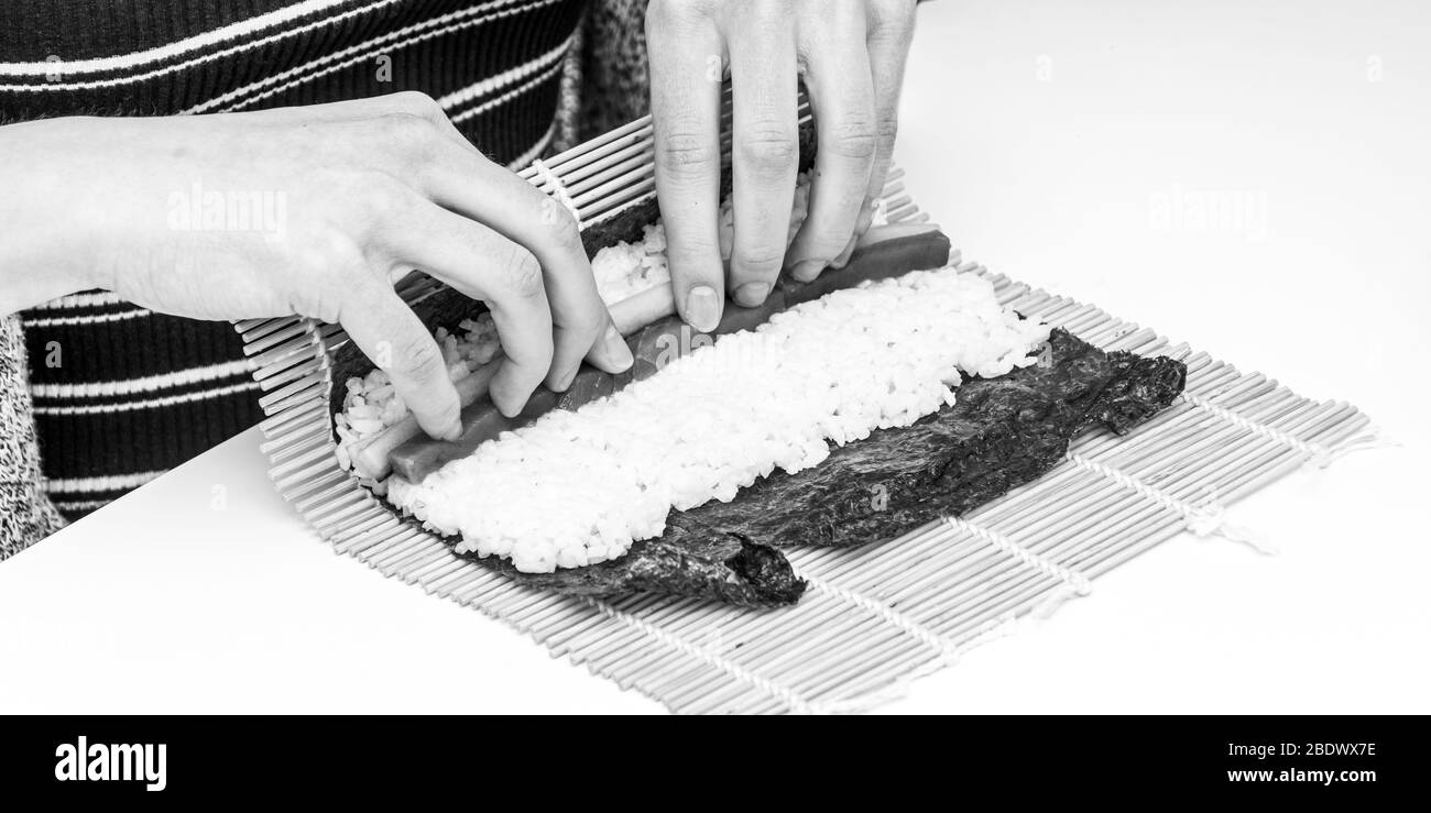 Sushi-Rolle Japanisches Gericht Thunfisch Gurke Zubereitung Zutaten in Algenblatt in schwarz und weiß gerollt Stockfoto