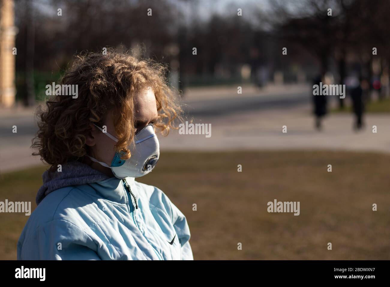 Mädchen mit Gesicht Schutzmaske im Freien. Kopieren Sie den Bereich auf verschwommenem Hintergrund. Konzept der Gesundheitsproblem. Schutz vor Viren und Krankheiten Stockfoto