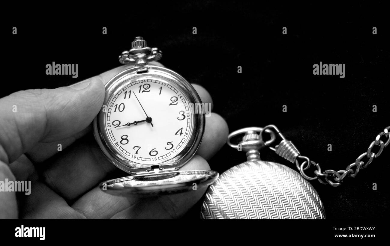 Zwei alte Taschenuhren, eine in der Hand gehalten. Eine ist offen, die andere geschlossen. Schwarzweiß-Fotografie Stockfoto