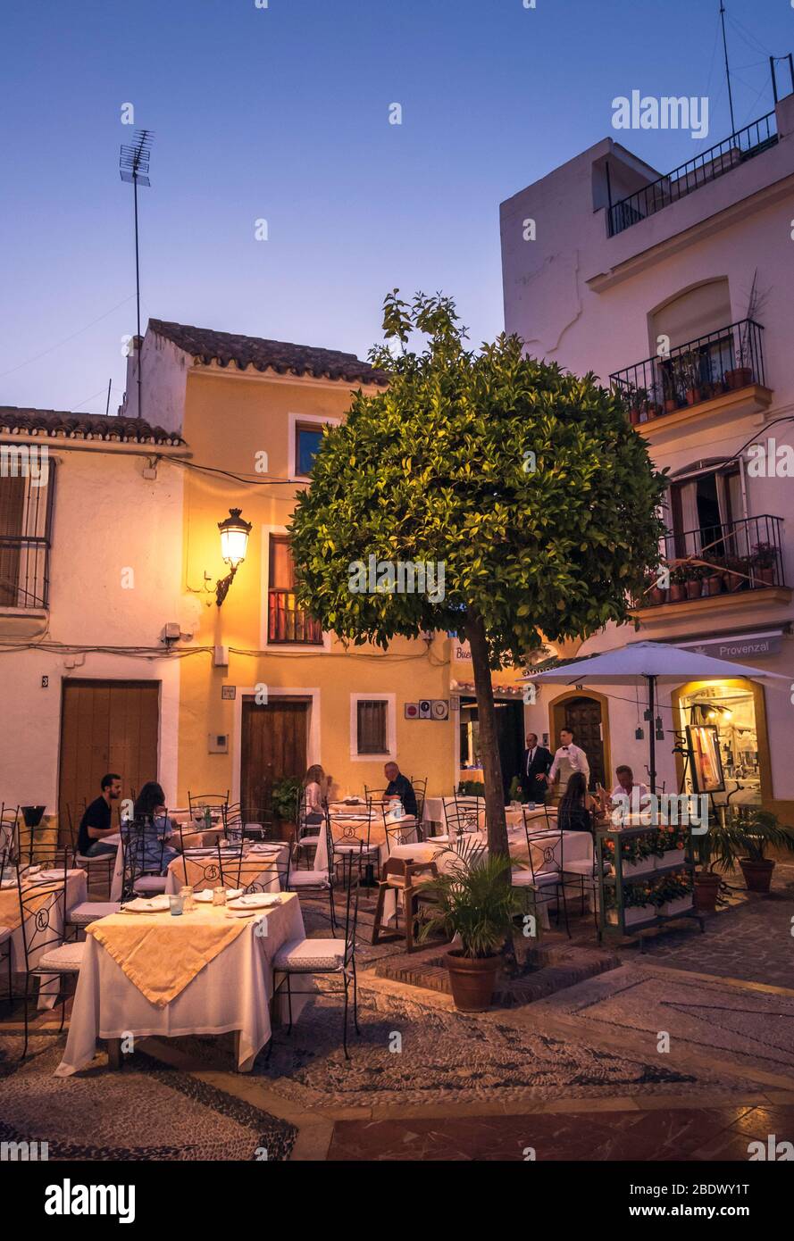 Leute, die außerhalb eines Restaurants auf einem gepflasterten Platz in der Altstadt von Marbella, Spanien essen. Stockfoto